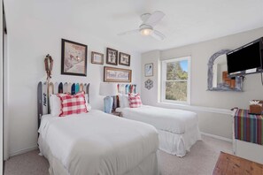 A bedroom with two beds, a ceiling fan, a window, and various framed pictures on the wall. - Ridge Home | Multi-level w/ PC Views, Ski Trail (Park City)