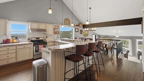 Una cocina amplia con una isla grande, taburetes de bar y vistas al exterior.