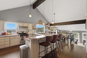 A spacious kitchen with a large island, bar stools, and a view of the outdoors. - Ridge Home | Multi-level w/ PC Views, Ski Trail (Park City)
