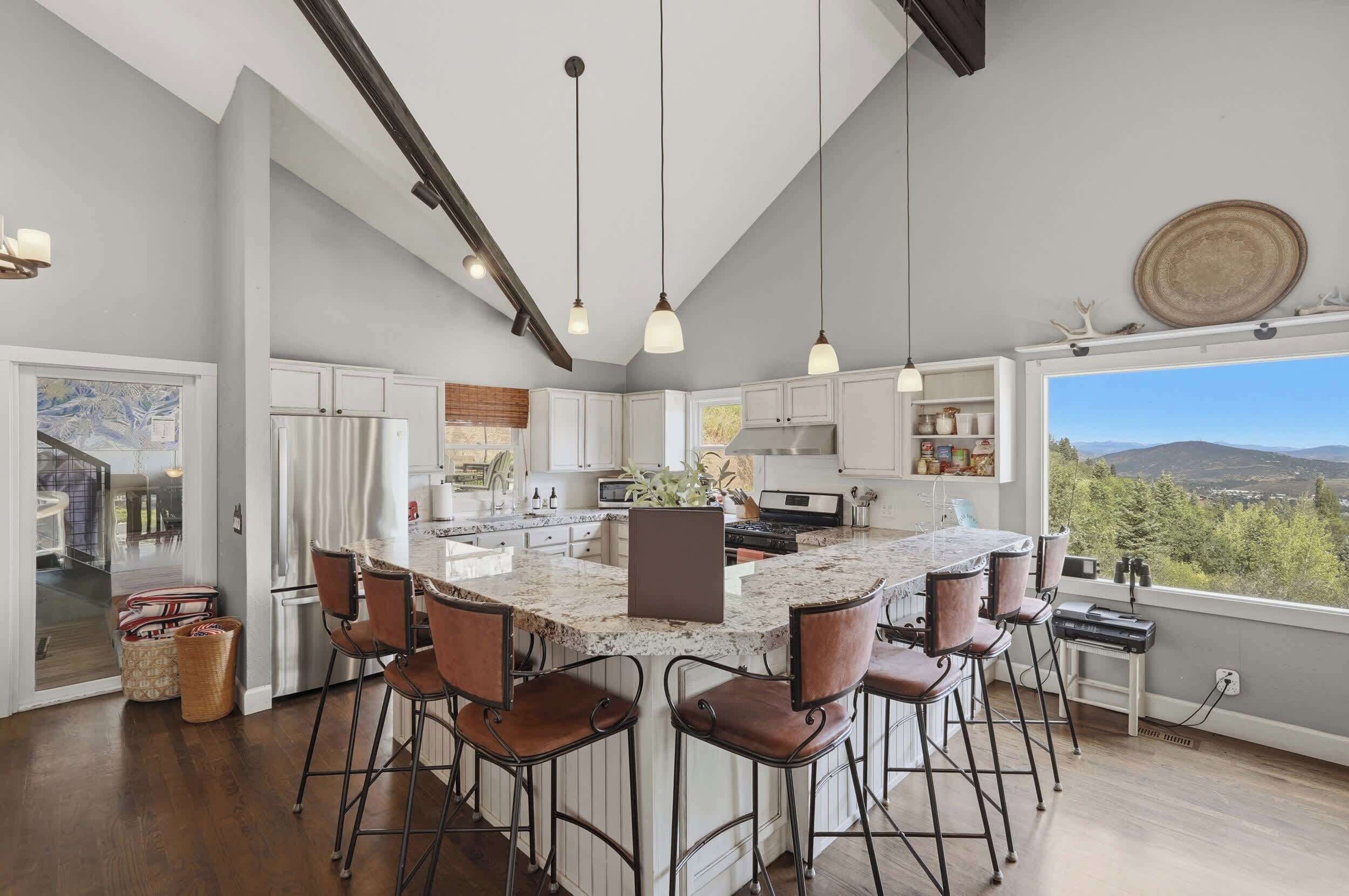 A spacious kitchen with a large island, bar stools, and pendant lighting.