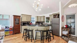 Una cocina amplia con una isla central, armarios de madera y una lámpara moderna.