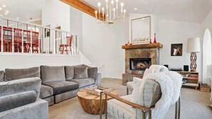A modern living room with a grey sectional sofa, a wooden coffee table, a fireplace, and a staircase with red chairs. - Treasure Hill House Ski-in Ski-out PCMR, sleeps 21 (Park City)