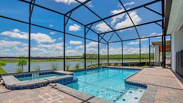 A swimming pool with a view of a lake, surrounded by a covered patio area. - 4300pw · Brand New Storey Lake 8BR Villa With Lake View (Kissimmee)