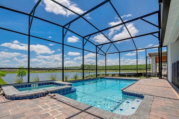 A swimming pool with a view of a lake, surrounded by a covered patio area. - 4300pw · Brand New Storey Lake 8BR Villa With Lake View (Kissimmee)