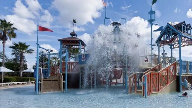 A water park with a central water feature, multiple slides, and a covered area with a red flag. - 4184pd · 20% OFF Weekly Stay/ 5br/free Water Park (Kissimmee)