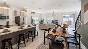 A modern kitchen with a central island, bar stools, and a dining area with a wooden table and chairs. - 4184pd · 20% OFF Weekly Stay/ 5br/free Water Park (Kissimmee)