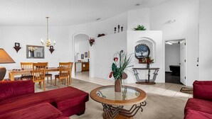 Een ruime woonkamer met rode banken, een houten eettafel en een glazen salontafel.