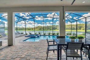 Un espacio exterior techado con piscina, sillas de descanso y una mesa con sillas.