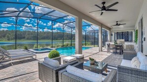 A covered patio area with a pool, outdoor seating, and a view of a lake. - 3017ps · Brand New Luxury 9BR Villa/ Pool/spa/game Room (Kissimmee)