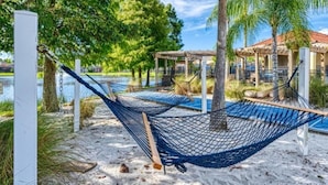 A hammock on a sandy beach with a pool and a gazebo in the background. - 201-4-hb-beautiful Home at Terraverde (Kissimmee)