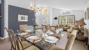 A dining area with a glass table set for six, surrounded by upholstered chairs. - 201-4-hb-beautiful Home at Terraverde (Kissimmee)