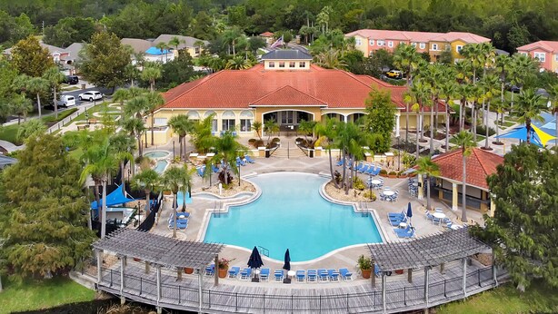 A resort with a central swimming pool, multiple buildings, and palm trees. - 4703 Flagler Beach Way, Kissimmee Florida,3bed (Kissimmee)