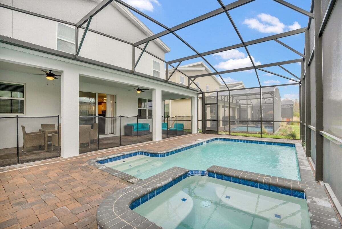 Piscina exterior techada con techo de vidrio, rodeada por un patio con asientos y vistas al paisaje.
