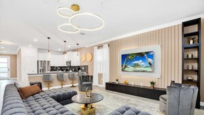 A modern living room with a large sectional sofa, a round coffee table, and a TV mounted on the wall. - 3016pl · Brand New High End 9BR Villa in Storey Lake Resort (Kissimmee)