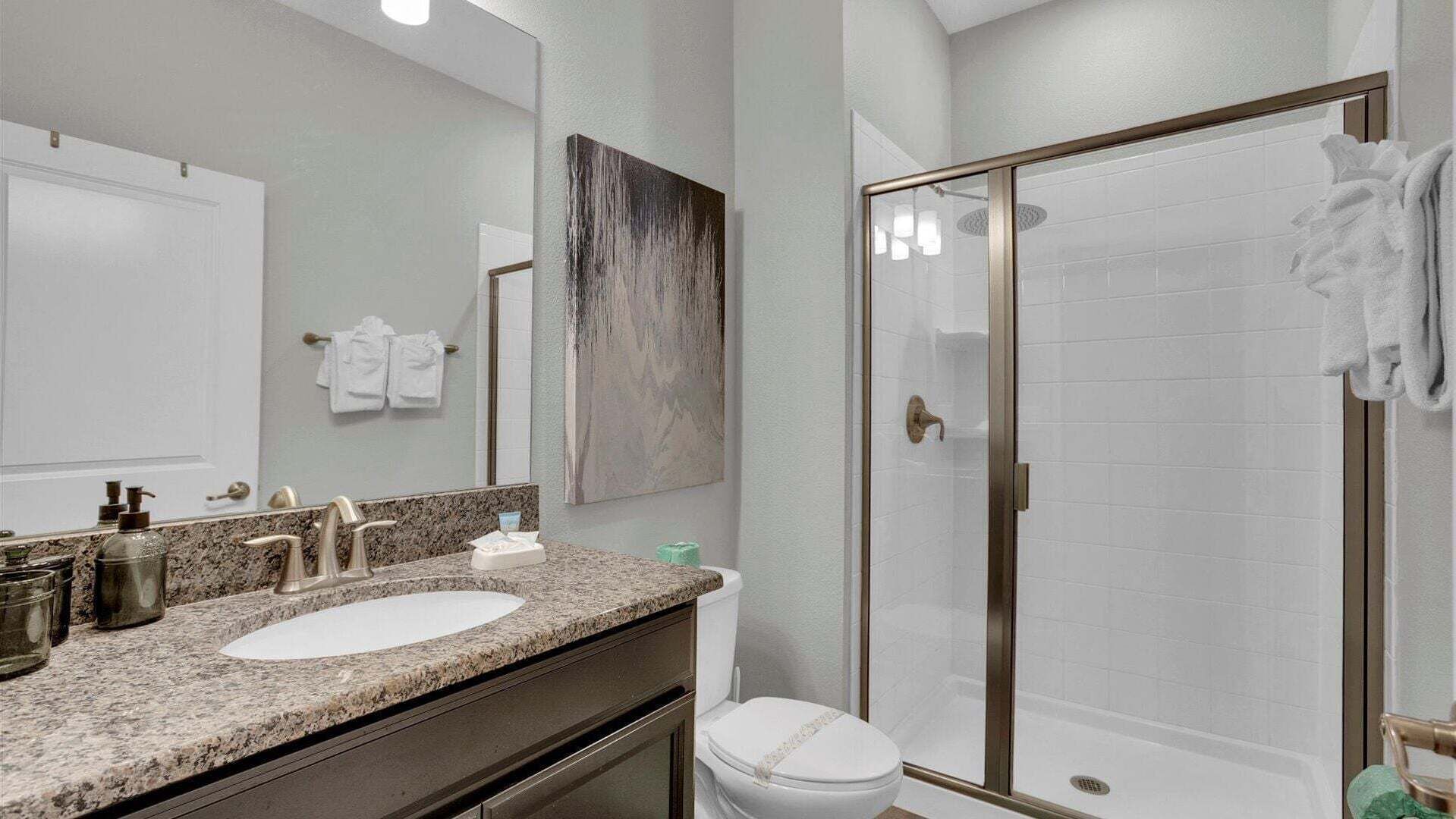 A bathroom with a double sink, a toilet, a shower with glass doors, and a large mirror.
