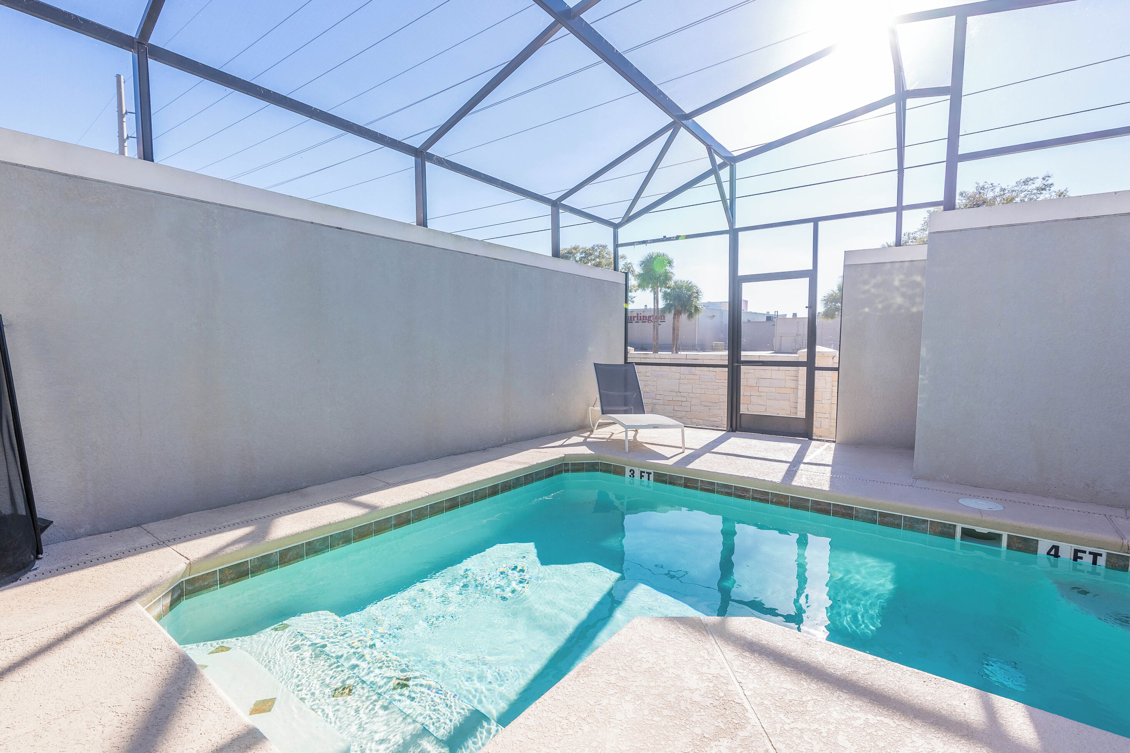An indoor swimming pool with clear water, surrounded by walls and a glass ceiling.