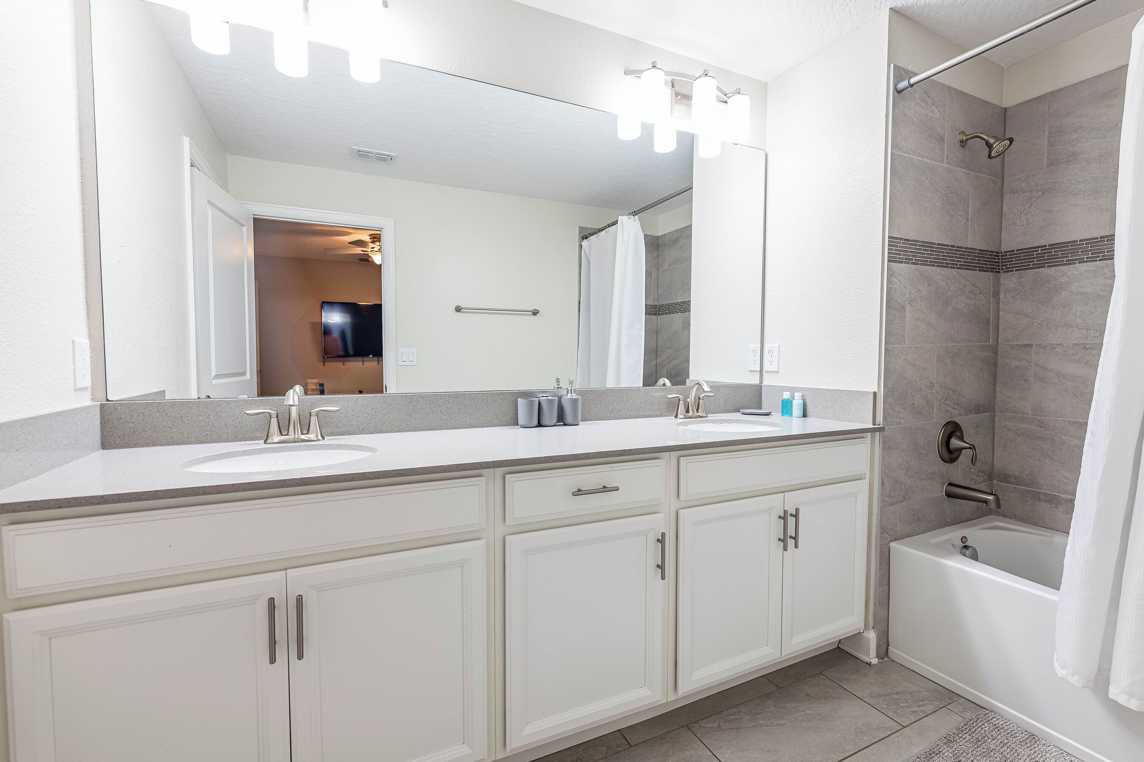 Une salle de bain moderne avec un meuble-lavabo à deux vasques, un grand miroir, une douche avec une porte en verre et une baignoire.