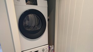 A compact laundry room with two stacked front-loading washing machines and a dryer. - Arrowtown Central Apartment with Sundeck (Arrowtown)