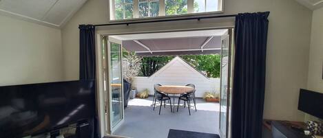 An open doorway leading to a patio with a table and chairs, a TV, and a desk with a computer.