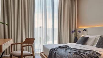 Ein modernes Hotelzimmer mit einem großen Bett, einem Schreibtisch und einem Stuhl.