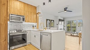 Une cuisine moderne avec des meubles en bois, des appareils électroménagers en acier inoxydable et un îlot central.