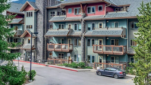 Un hôtel à plusieurs étages, doté de balcons, d’une façade en pierre et surplombant un paysage montagneux.