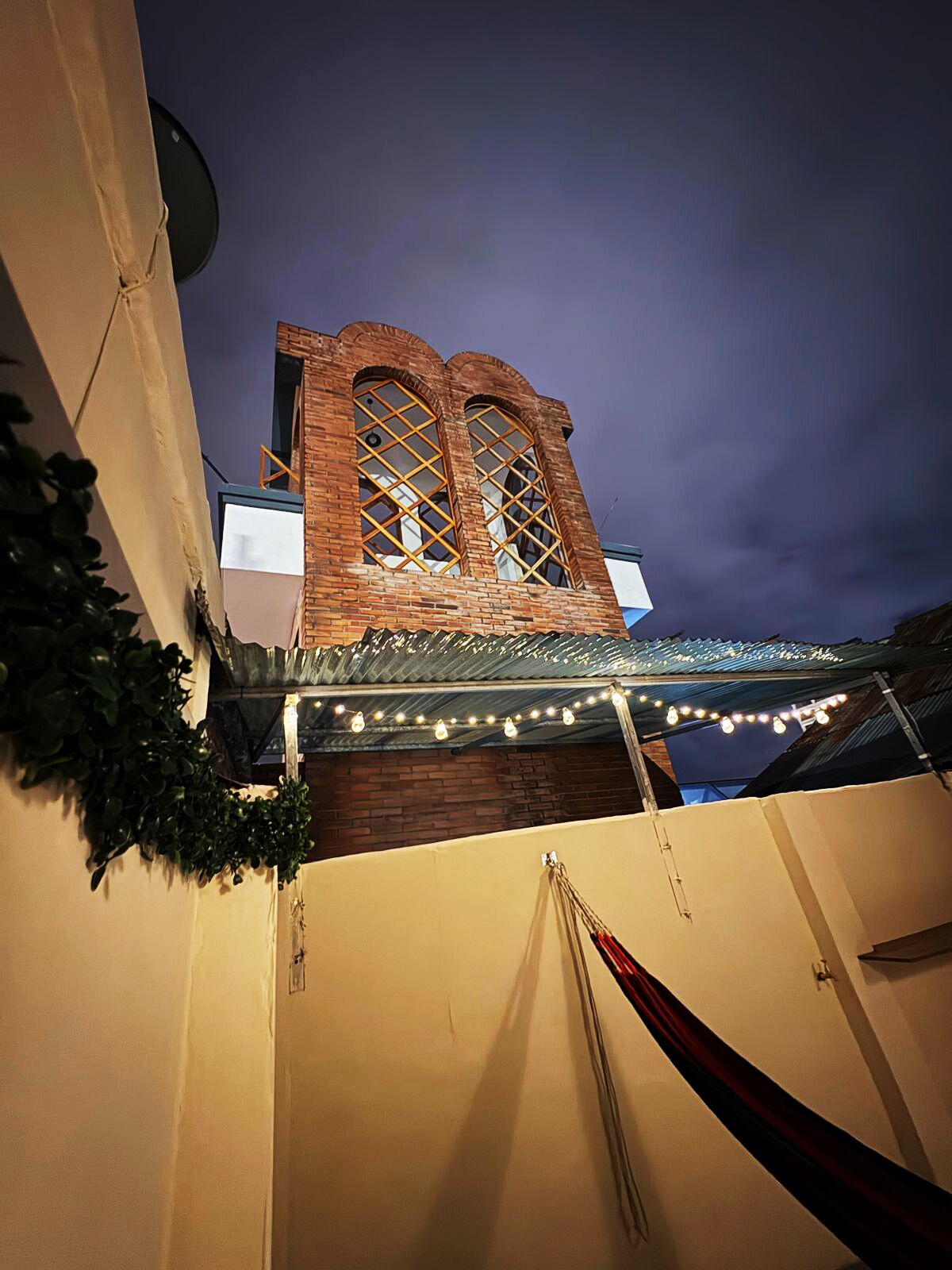 A brick tower with arched windows and a covered area with string lights.