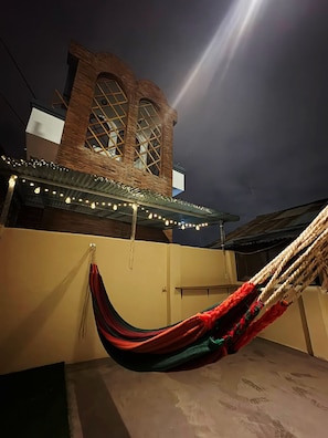 A hammock under a covered area with string lights, a brick building in the background, and a clear sky. - New Apt+Work Area+Private Terrace+WiFi+Tv (Quito)