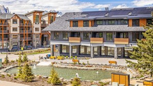 Un hotel moderno con piscina, mobiliario exterior y vistas a la montaña.