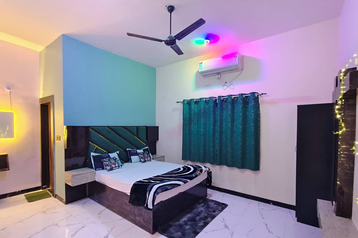 A bedroom with a bed, a ceiling fan, an air conditioning unit, and a window with curtains.