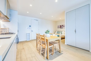 A modern kitchen with wooden chairs, a dining table, and a white cabinet. - StayAU Convenient City Apt in West Melb (West Melbourne)