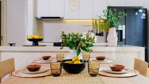 A modern kitchen with a dining table set for four, featuring a vase with green leaves and lemons, and a refrigerator in the background. - Discover a private pool villa designed for comfortable long-term living. (Tambon Rawai)
