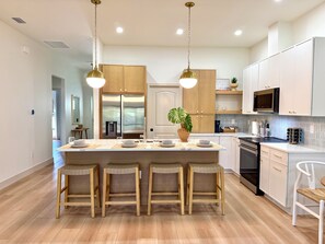 A modern kitchen with a central island, wooden cabinets, stainless steel appliances, and a seating area with stools. - Tranquil 3-bedroom townhome with AC in Port Charlotte Boca grande Beach near by (Port Charlotte)