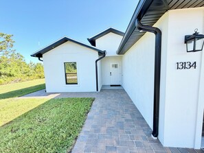 A modern house with a paved driveway leading to a white door, a small attached garage, and a mailbox with the number 13134. - Light House – Coastal Retreat near Boca Grande (Port Charlotte)