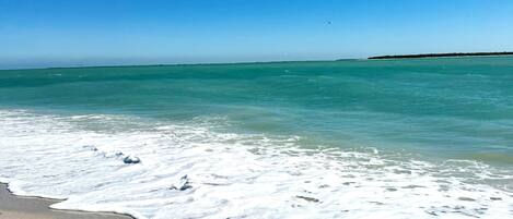 A beach with clear turquoise water and a sandy shore.