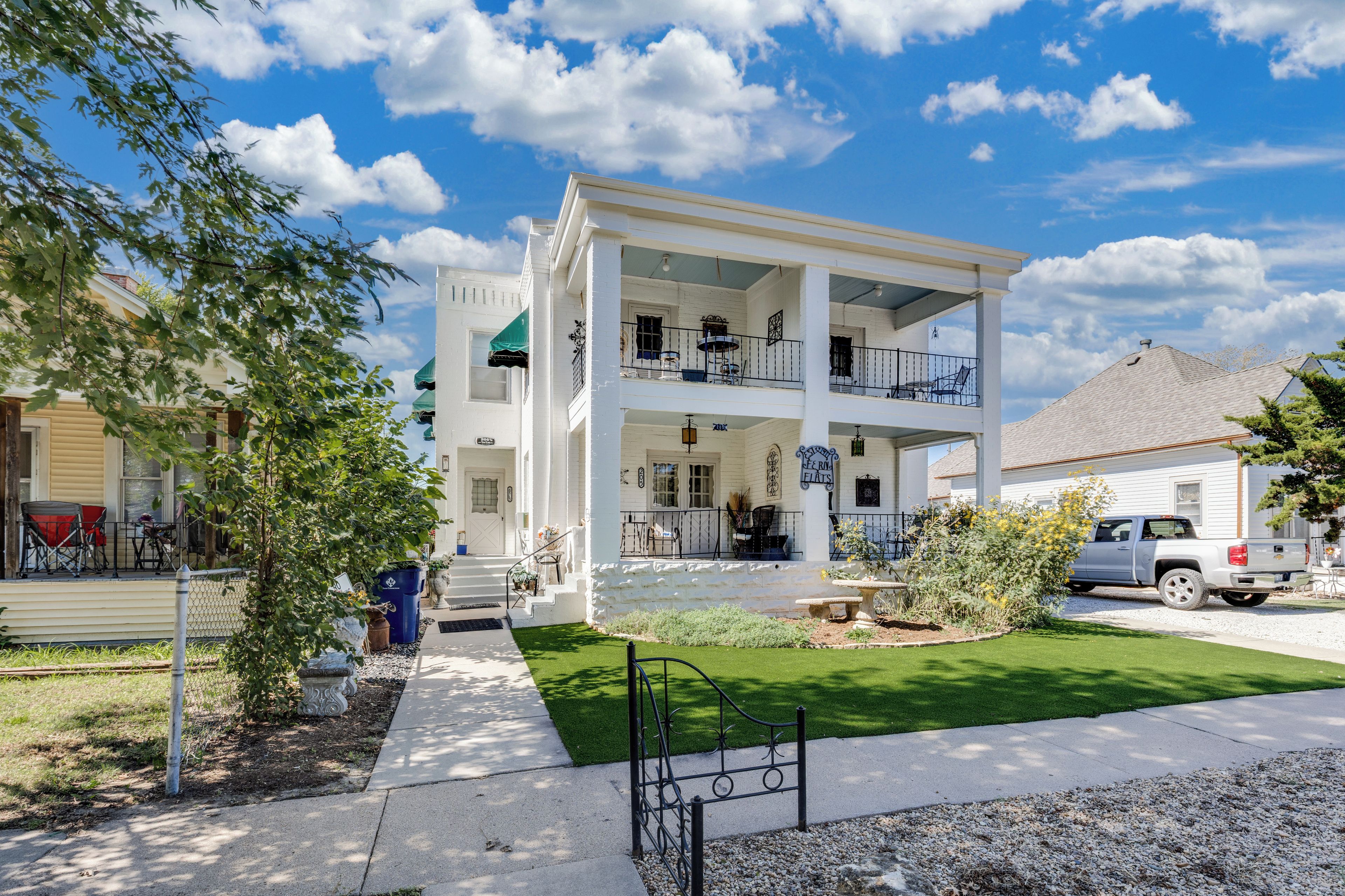 A two-story building with a covered front porch, a stone foundation, and a well-maintained lawn.
