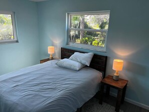 A bedroom with a bed, two bedside tables, and a window with a view of greenery. - Ashota - The Agave (Venice)