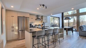 Een moderne keuken met een centraal eiland, barstoelen en een zithoek met een bank.