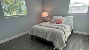 Una camera da letto con un letto, un comodino, una lampada e una finestra.