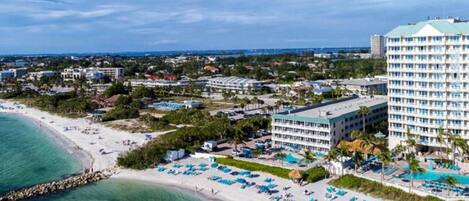 A coastal hotel with a beachfront, multiple swimming pools, and a large building with numerous balconies.