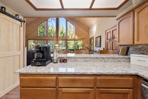 A kitchen with a large island, wooden cabinets, and a coffee maker.
