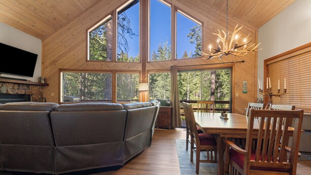 A spacious living area with a large sectional sofa, a dining table with chairs, and a chandelier.