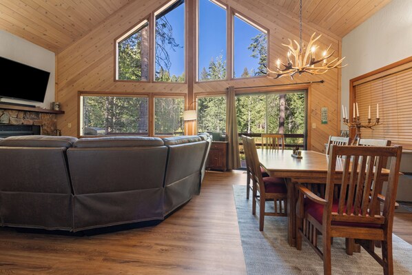A spacious living area with a large sectional sofa, a dining table with chairs, and a chandelier.