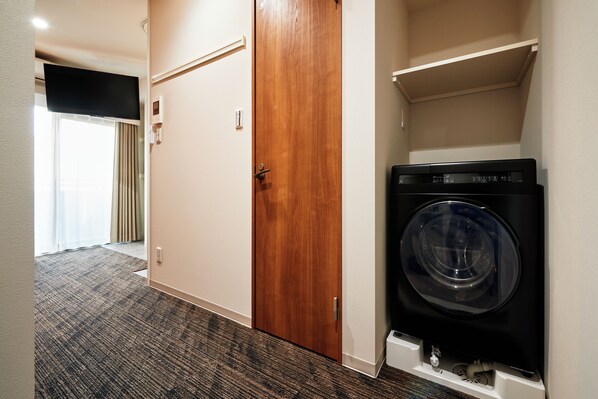 A laundry room with a washing machine, a wooden door, and a carpeted floor. - Moat Inside Tenjin (Fukuoka)