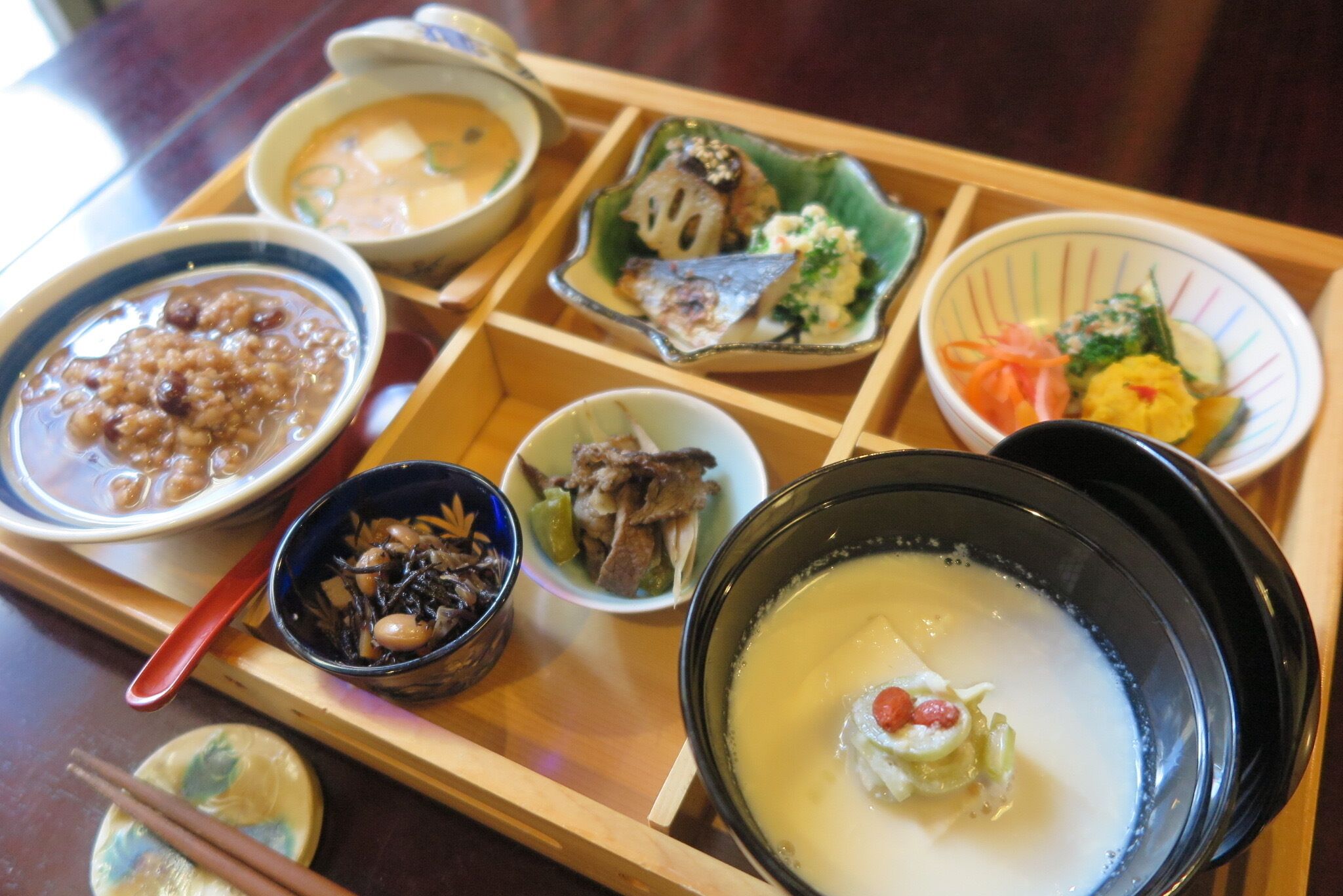 A tray with various dishes including a bowl of soup, a bowl of rice, and several small plates with different foods.