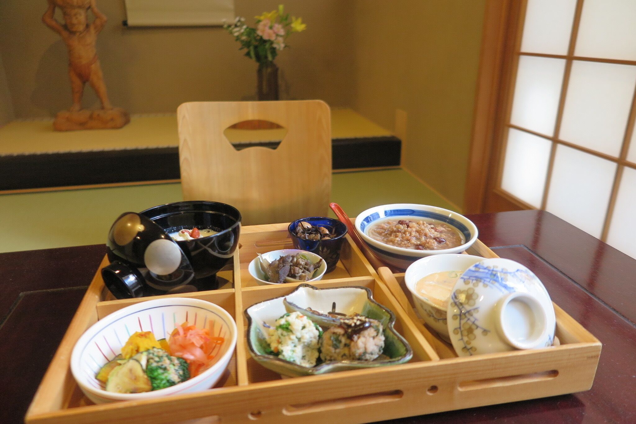 A wooden tray with various dishes, including sushi and bowls, on a table.