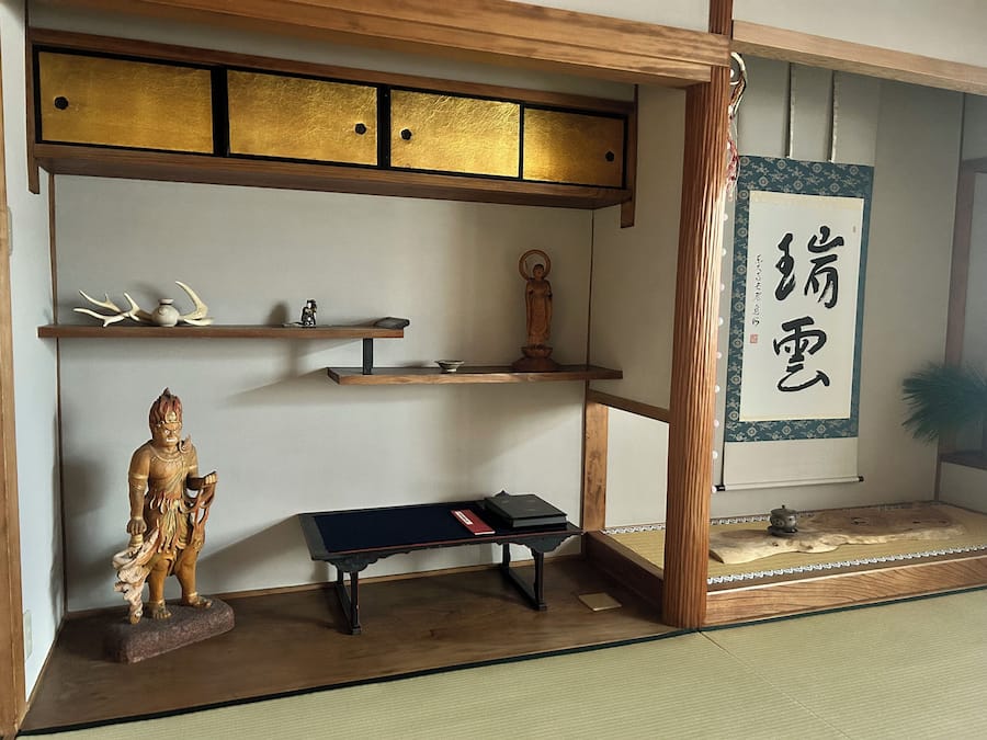 A traditional Japanese room with tatami flooring, a shoji screen, and a calligraphy scroll.