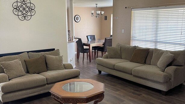 A living room with two beige sofas, a wooden coffee table, a ceiling fan, and a dining area in the background. - Kindness Dwells (Killeen)