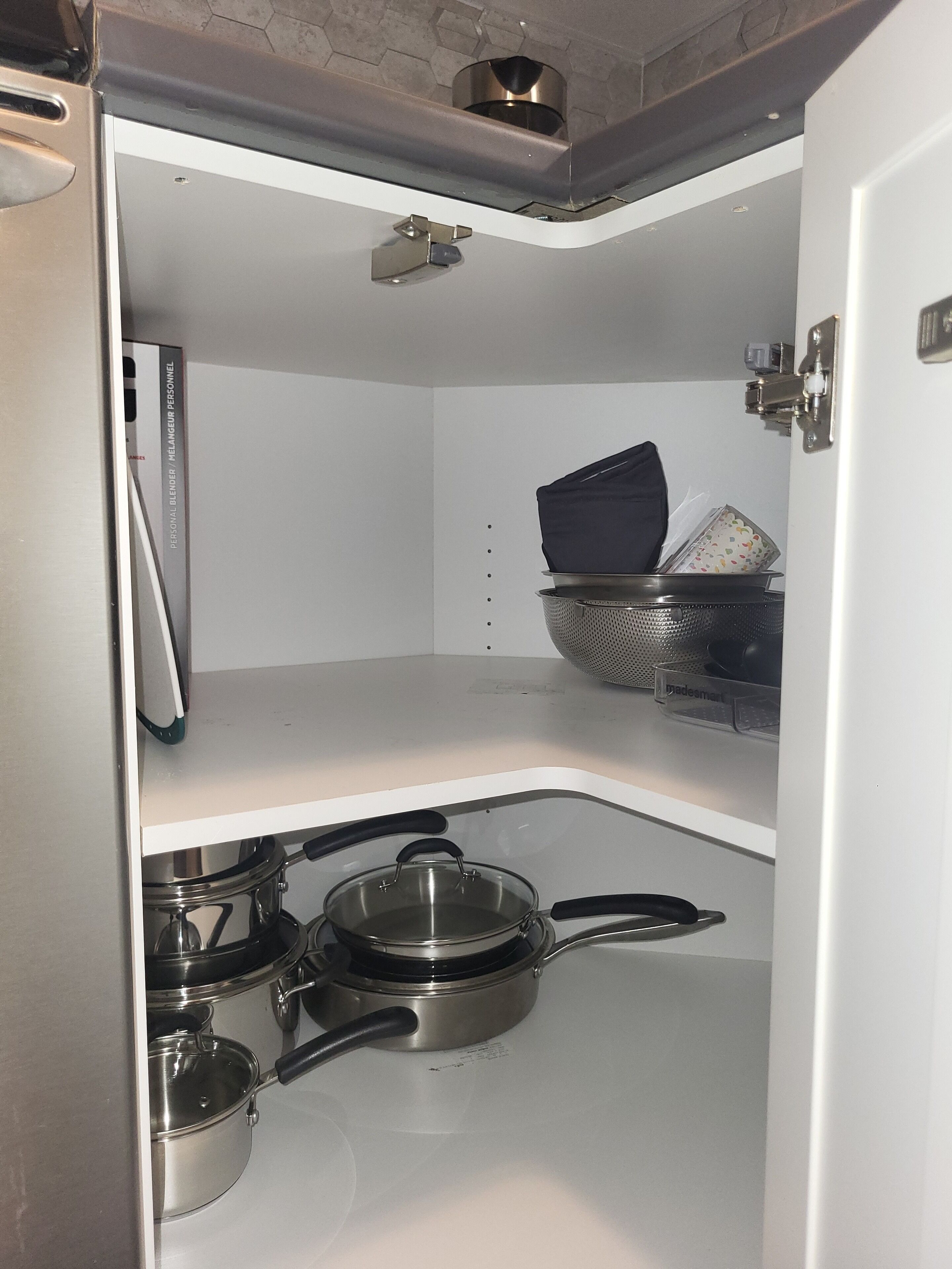 A compact kitchen with a built-in stove, a sink, and a small storage area with pots and a colander.