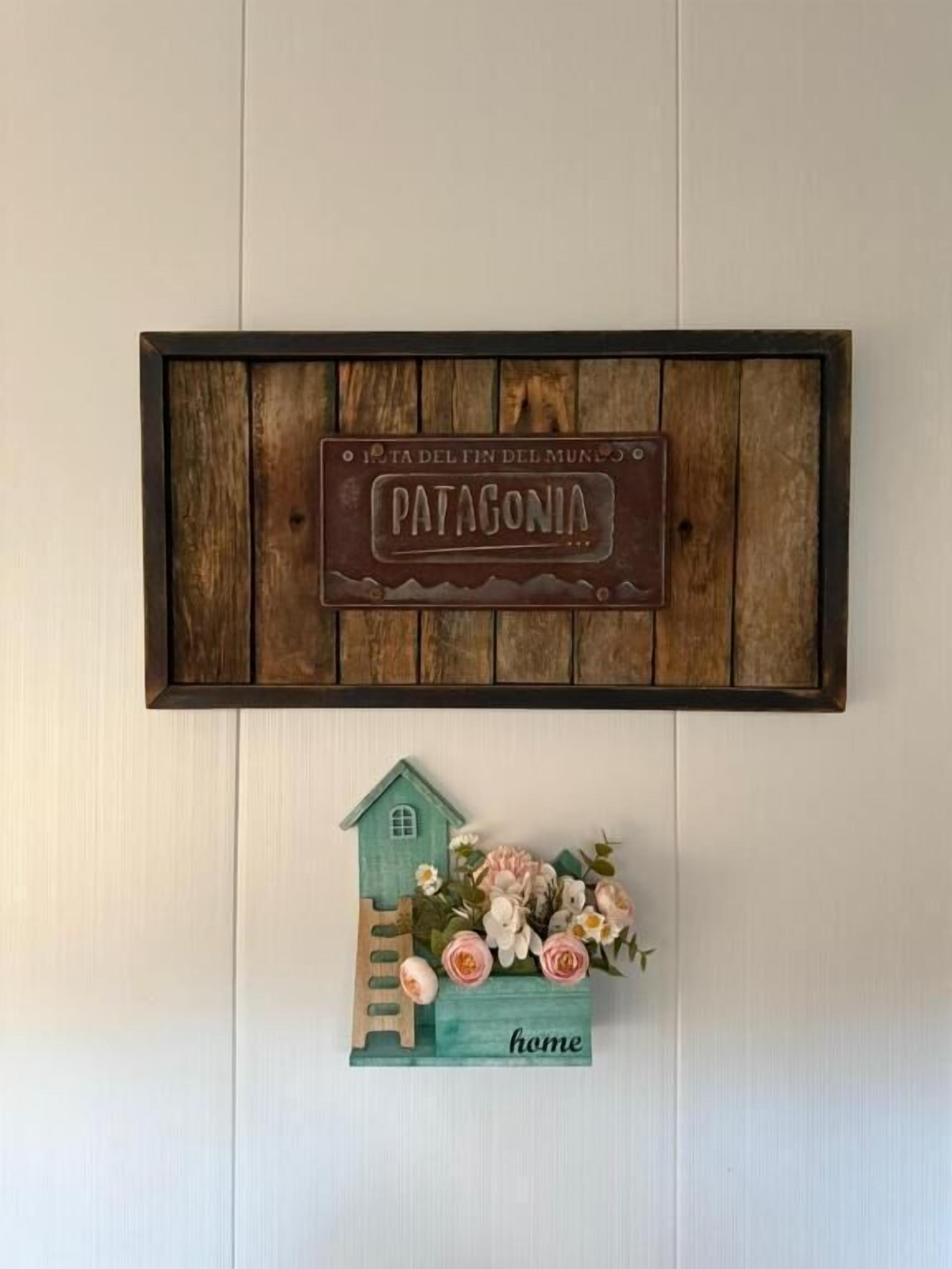 Une enseigne rustique en bois, sur laquelle est inscrit le mot « Patagonie », et une petite décoration représentant une maison en dessous.